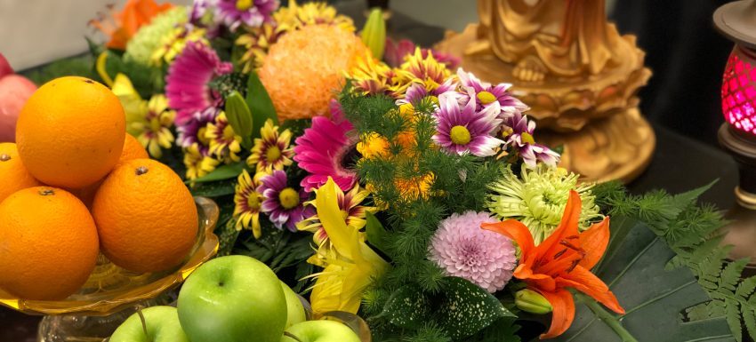 Fresh floral and fruit offerings on a Buddhist altar